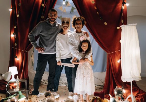 A joyful family enjoying imaginative play in a home theatre setting with costumes and creativity.