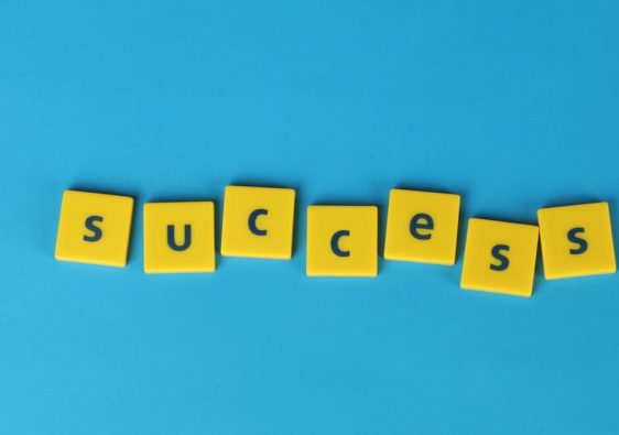 Yellow letter tiles spell the word success on a vibrant blue backdrop, symbolizing achievement.