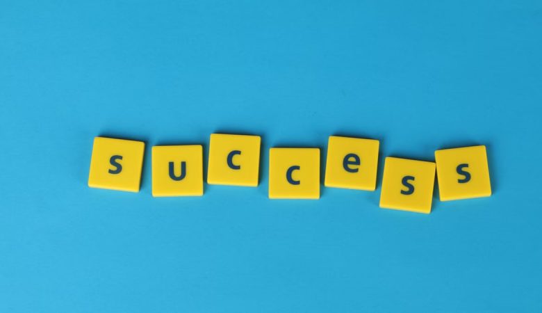 Yellow letter tiles spell the word success on a vibrant blue backdrop, symbolizing achievement.